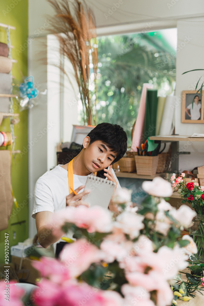 小生意。男花店老板在花店柜台制作玫瑰花束。男助理或其他