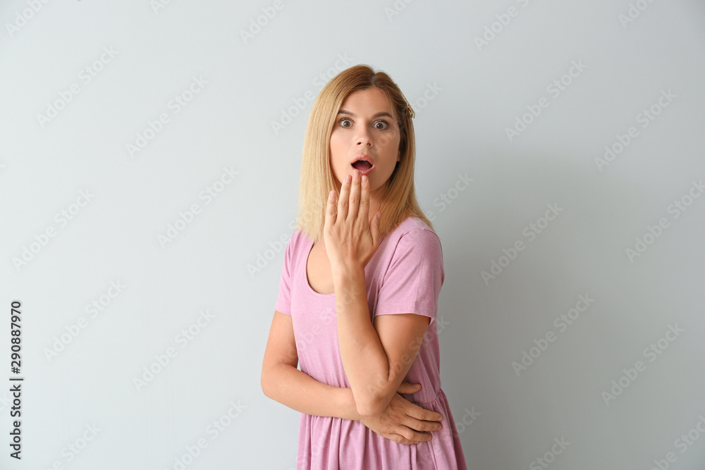 Shocked beautiful woman on light background