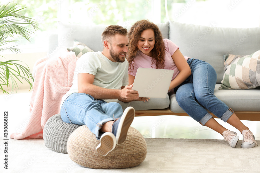 Happy young couple with laptop relaxing at home