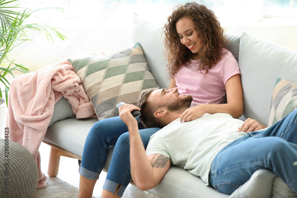 Happy young couple relaxing on sofa at home