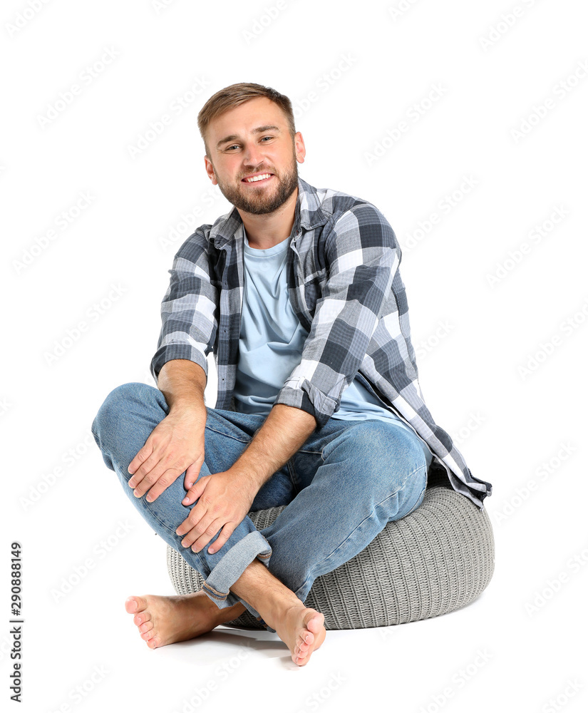 Handsome young man sitting on pouf against white background