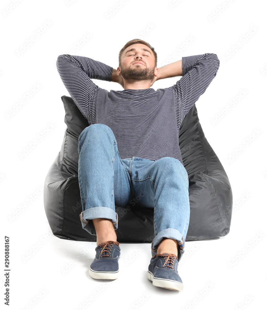 Handsome young man relaxing on beanbag against white background