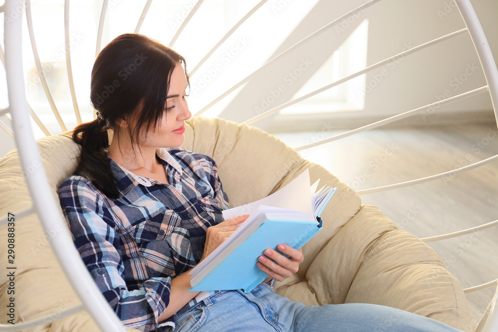 Beautiful young woman reading book at home