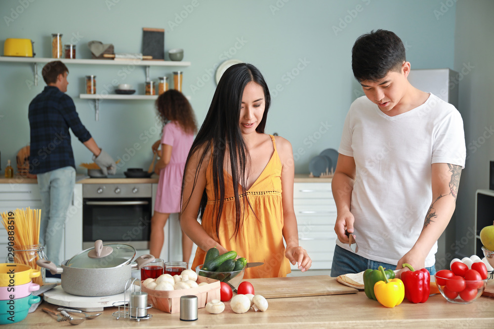 Happy Asian couple cooking together in kitchen