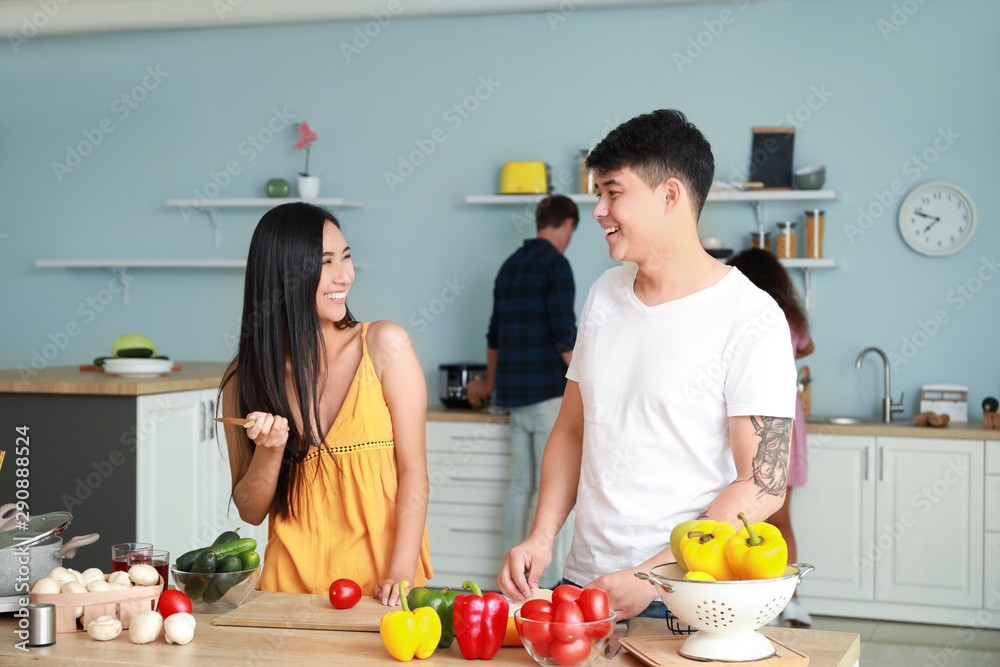 Happy Asian couple cooking together in kitchen