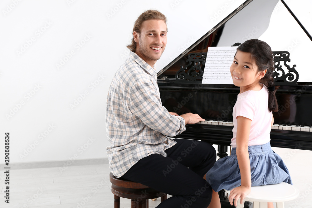 Man teaching little girl to play piano