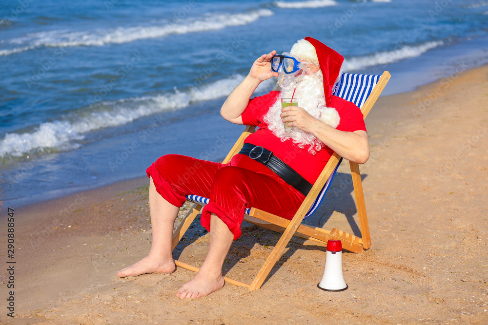 Happy Santa Claus with cocktail and mask resting at sea resort