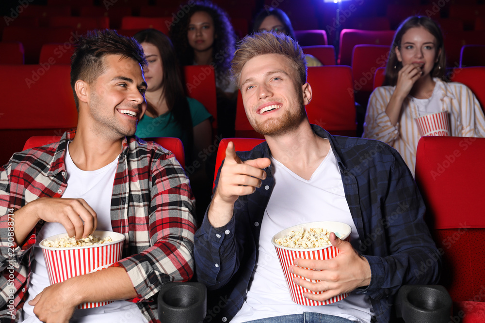 Friends with popcorn watching movie in cinema