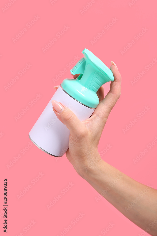 Female hand with bottle of air freshener on color background