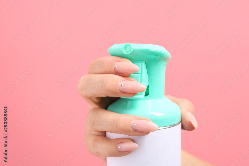 Female hand with bottle of air freshener on color background, closeup