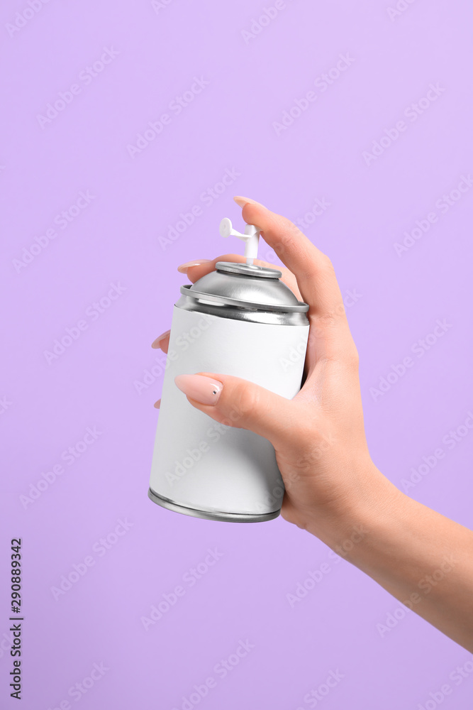 Female hand with bottle of air freshener on color background