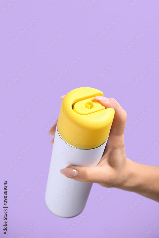 Female hand with bottle of air freshener on color background