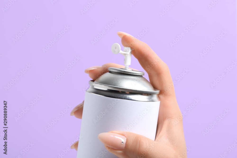 Female hand with bottle of air freshener on color background, closeup