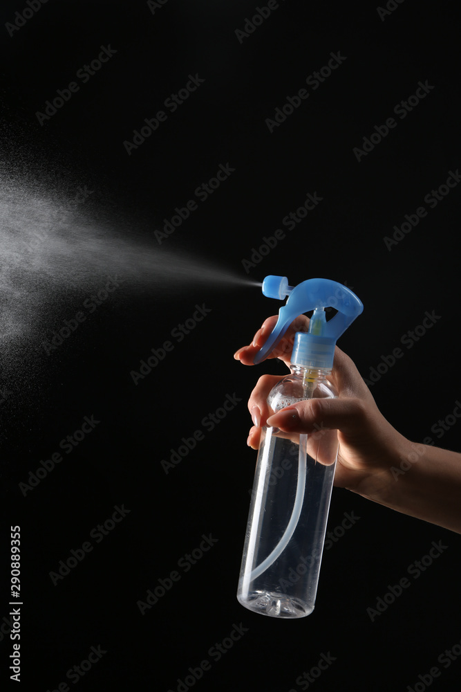 Female hand with bottle of air freshener on dark background