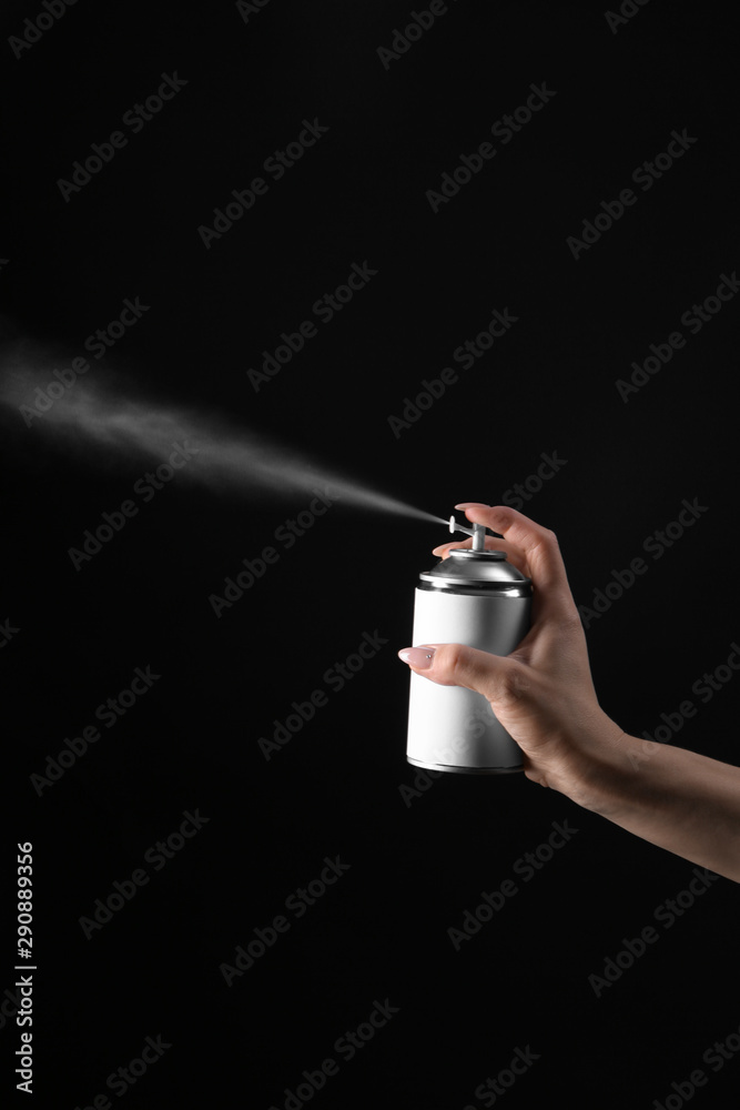 Female hand with bottle of air freshener on dark background