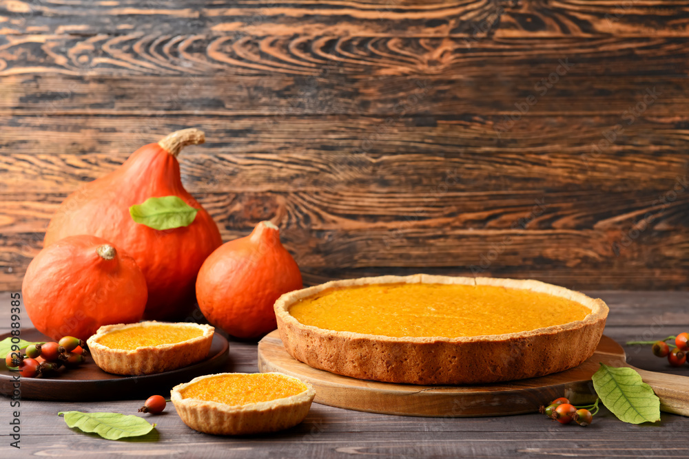 Tasty pumpkin pies on wooden background