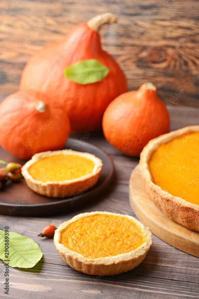 Tasty pumpkin pies on wooden background