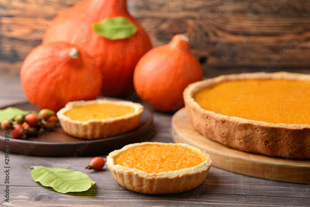 Tasty pumpkin pies on wooden background