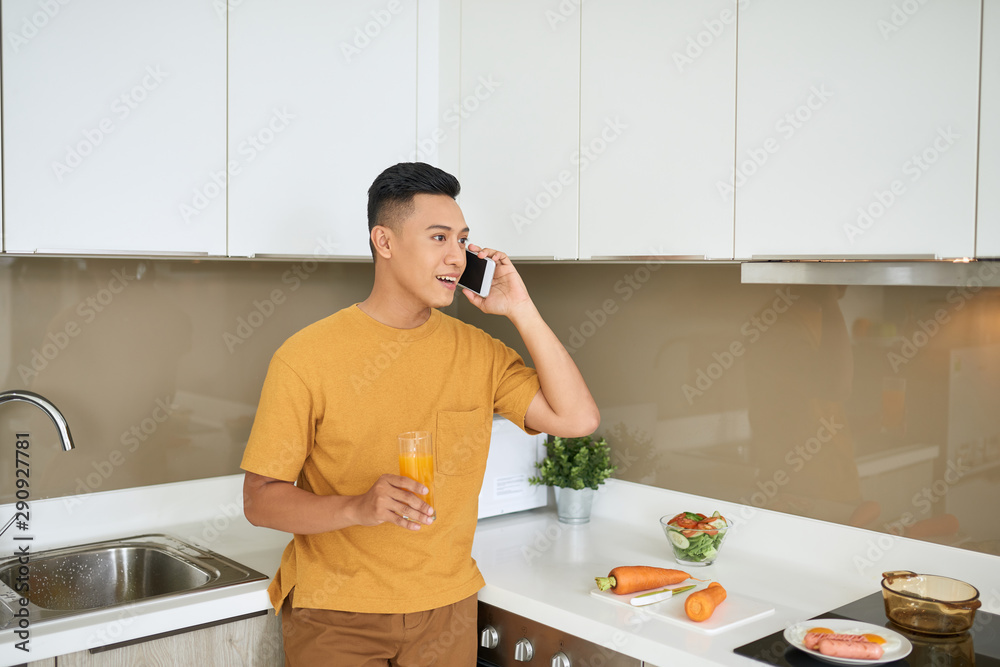 Handsome bachelor 30s talking on mobile phone, while having breakfast in morning