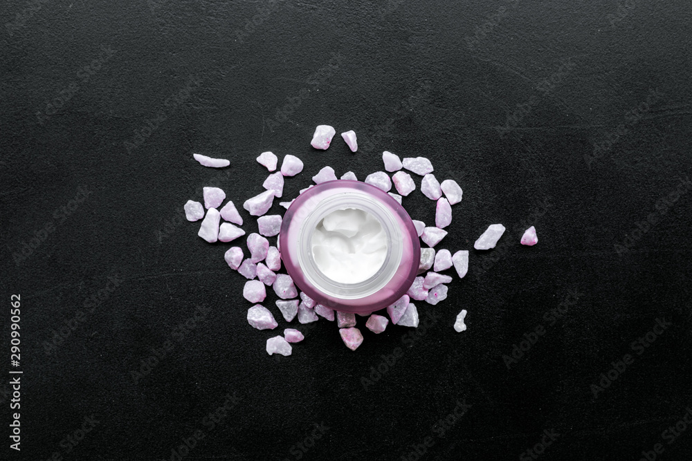 Cosmetics with sea salt decoration on black background top view