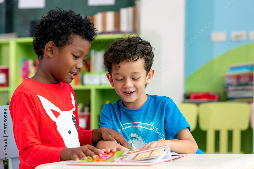 Student in international preschool reading a magazine book together in school library