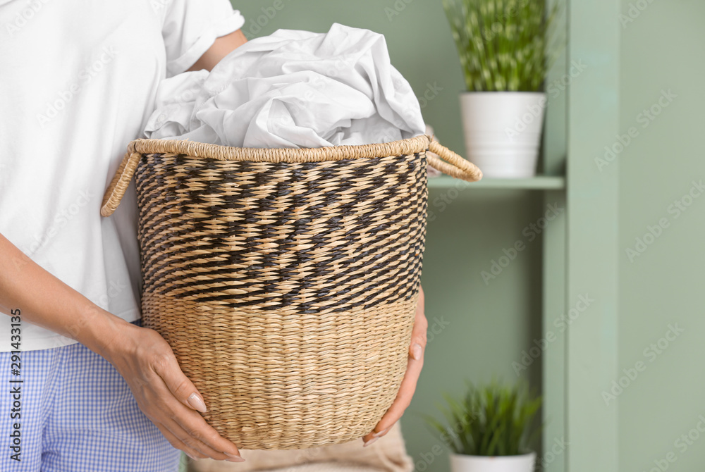 Woman holding basket with laundry at home