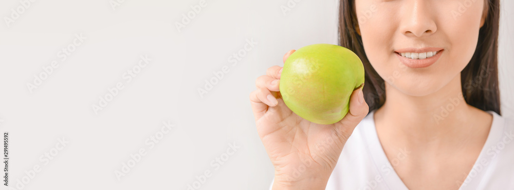 Beautiful Asian woman with toothbrush and paste on light background