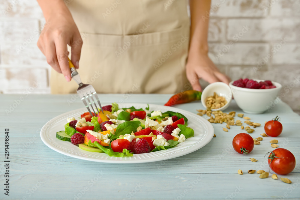 Woman eating tasty salad at table, closeup