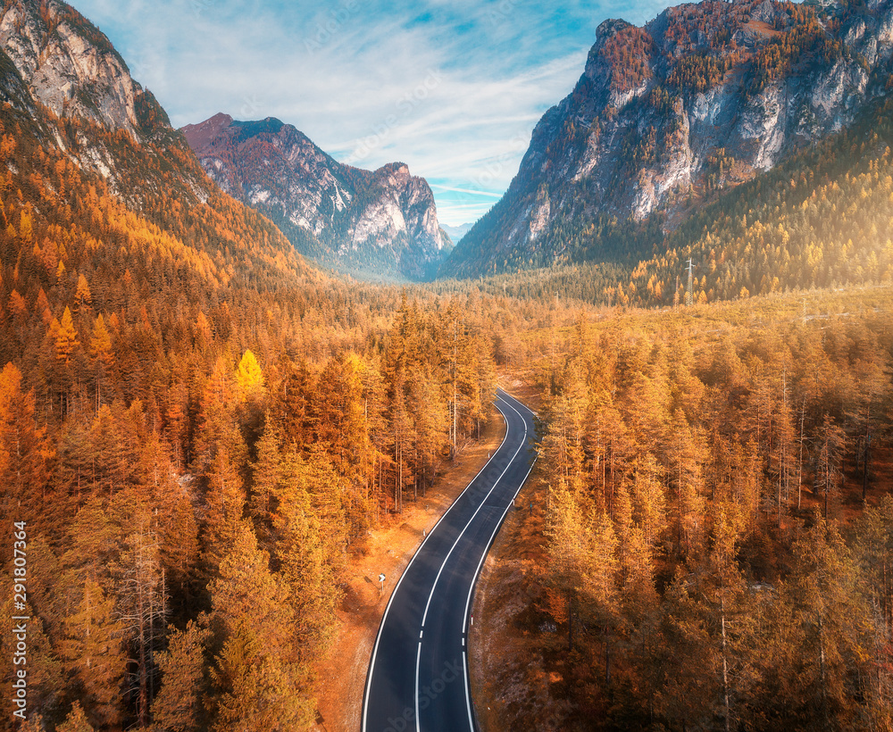 Aerial view of the mountain road in beautiful autumn forest at sunset. Top view of asphalt roadway, 