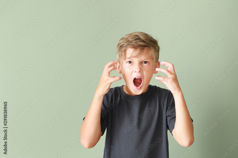 Portrait of angry little boy on color background