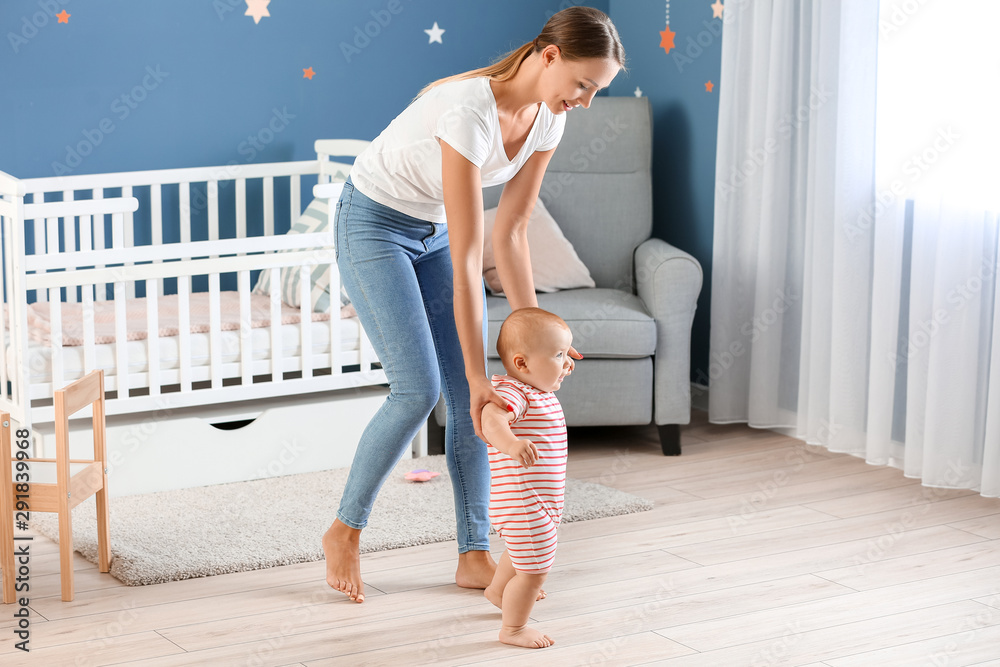 Mother teaching her little baby to walk at home