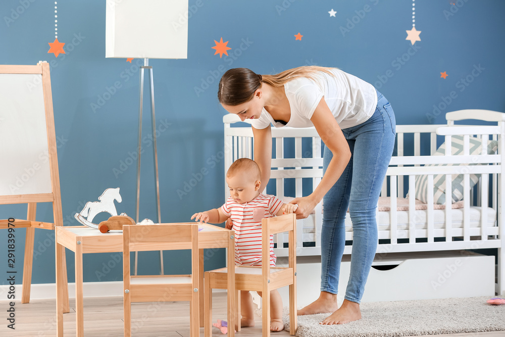 Mother teaching her little baby to walk at home