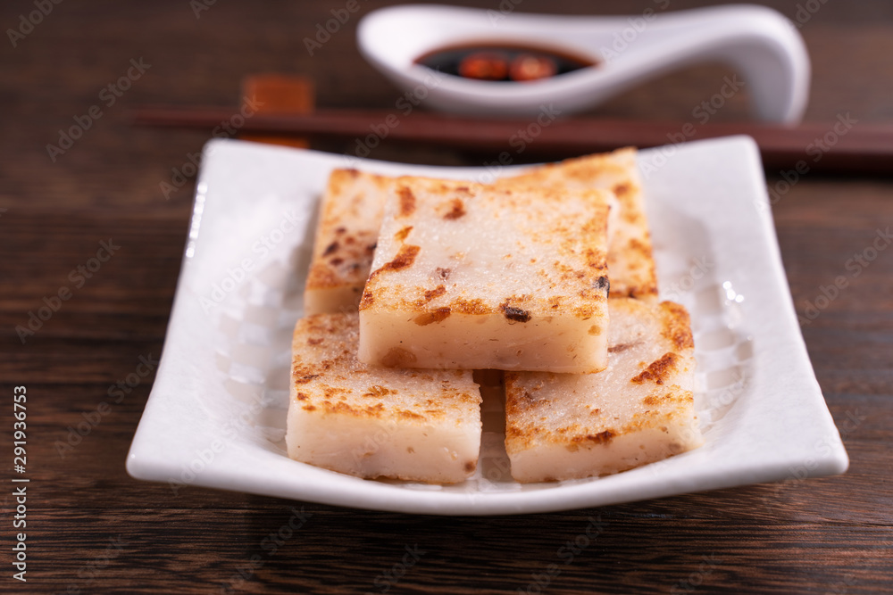 Delicious turnip cake, Chinese traditional local dish radish cake in restaurant with soy sauce and c