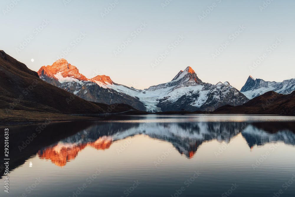 Bachalpsee lake with reflection in Swiss Alps mountains. Glowing snowy peaks on background. Grindelw