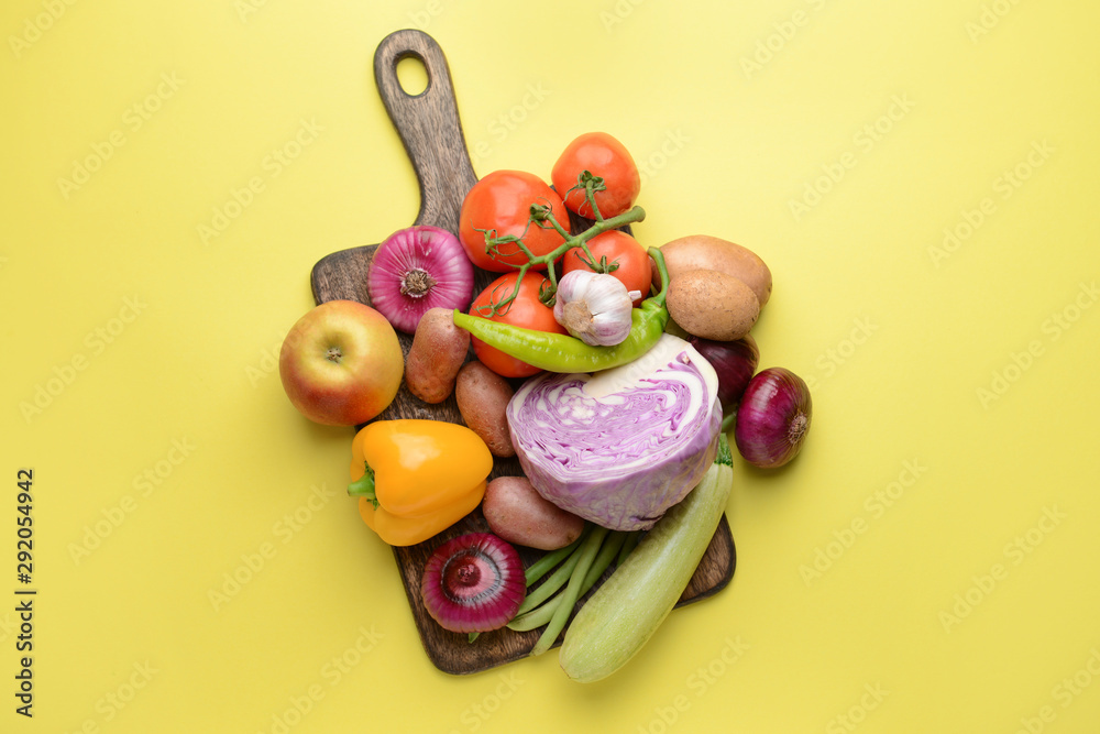 Board with many healthy vegetables on color background