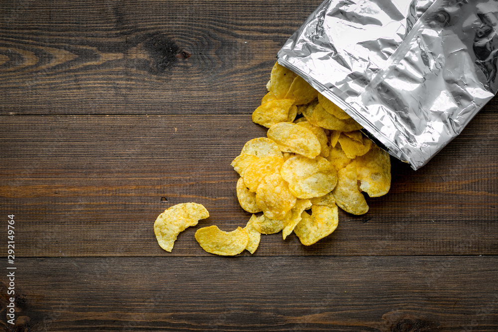 Bag of homemade potato chips for snack on wooden background top view copyspace