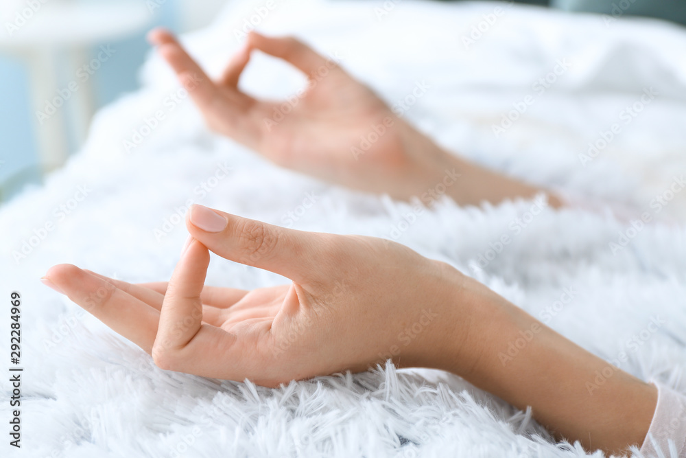 Young woman practicing yoga on bed at home, closeup