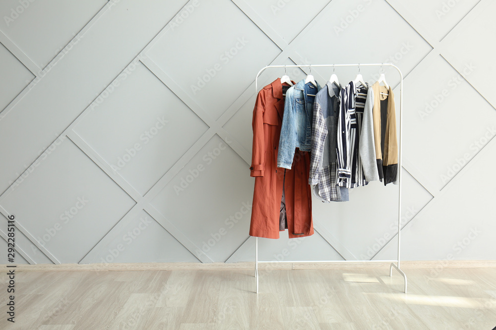 Rack with hanging clothes near light wall