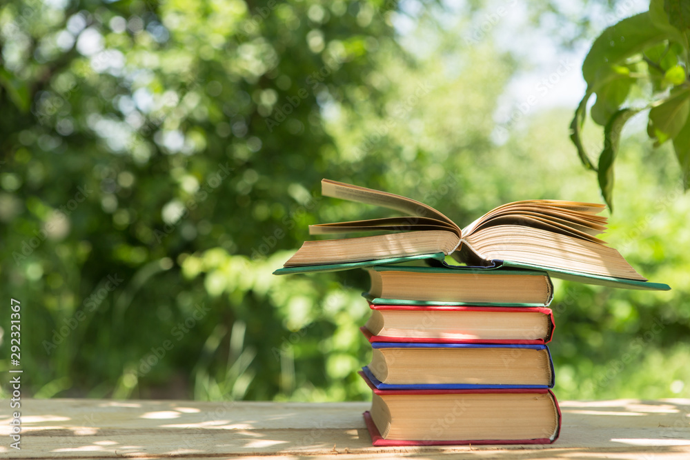 Open book on a wooden table in a garden. Sunny summer day, reading in a vacation concept