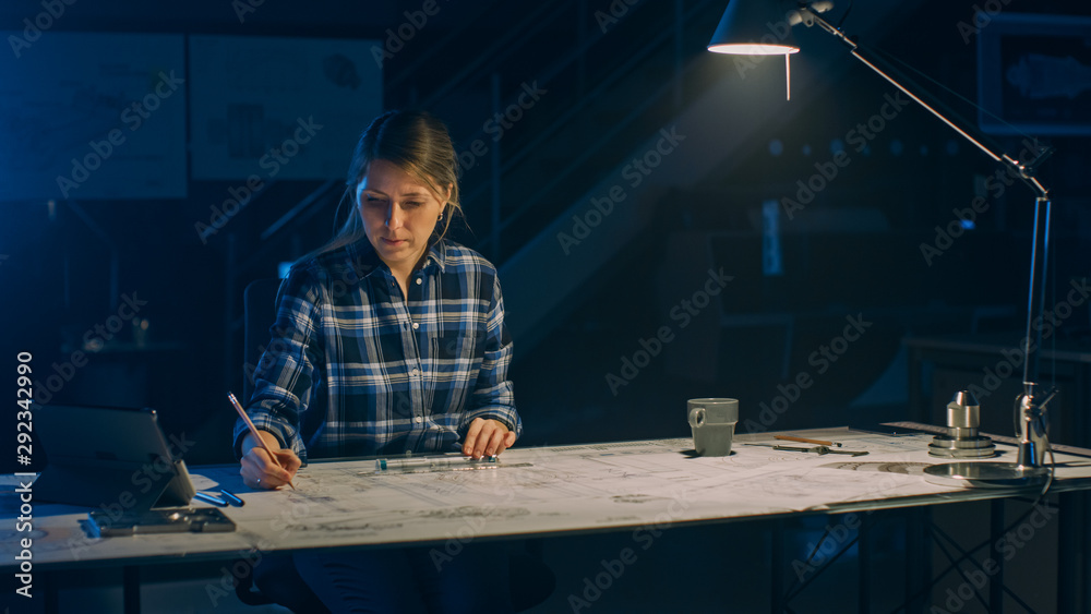 Female Engineer Sitting at Her Desk Works with Blueprints Laying on a Table, Uses Pencil, Ruler and 