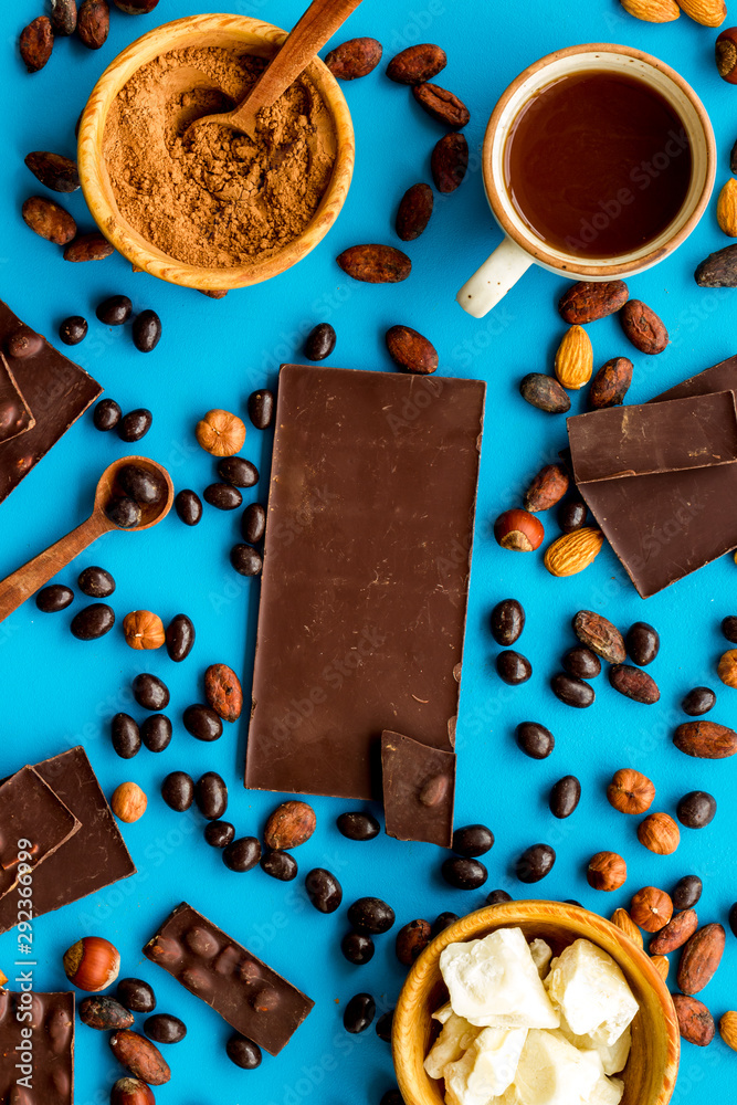 Cook homemade chocolate with bars, nuts, coffee beans on blue background top view