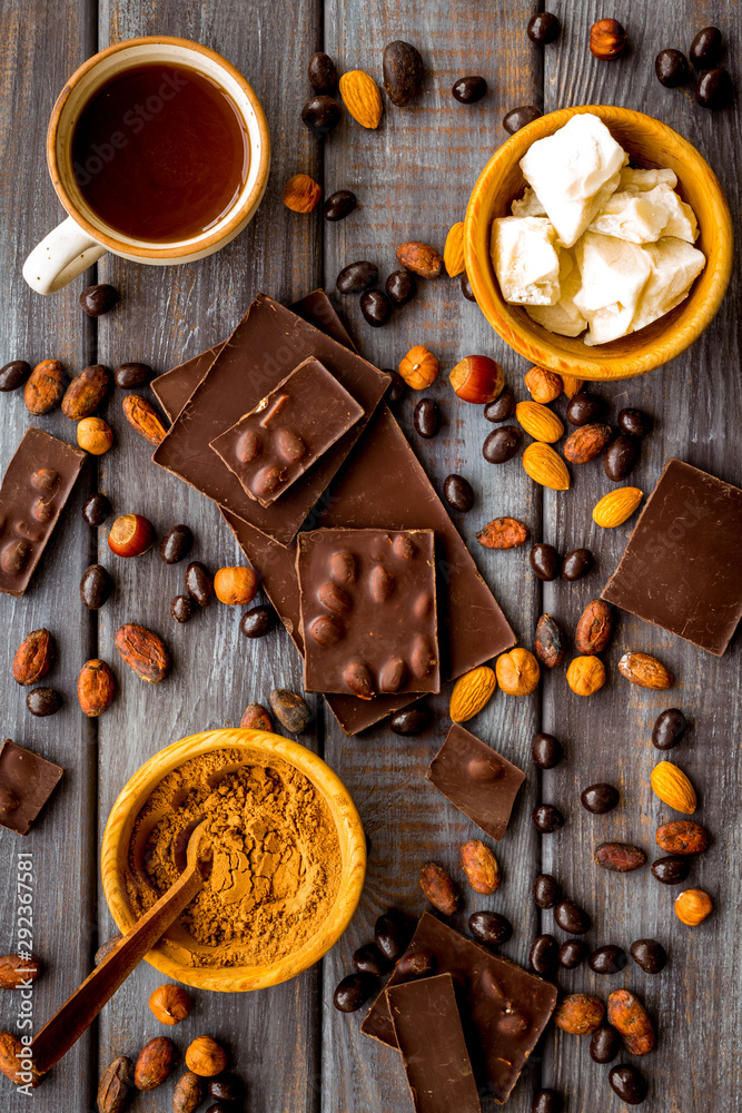 Tea with homemade chocolate bars, nuts, coffee beans on wooden background top view