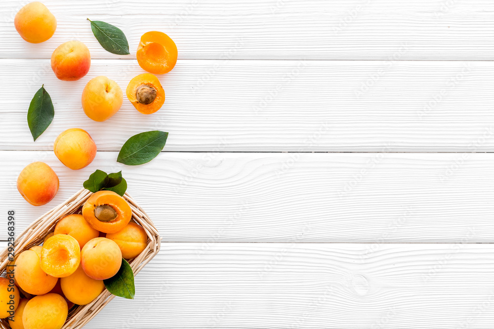 Collect apricots, white wooden background top view copy space, pattern with leaves