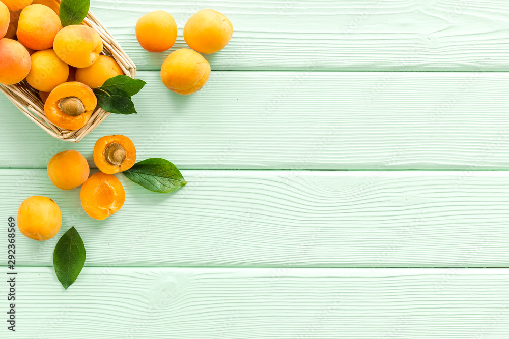 Collect apricots, green wooden background top view copy space, pattern with leaves