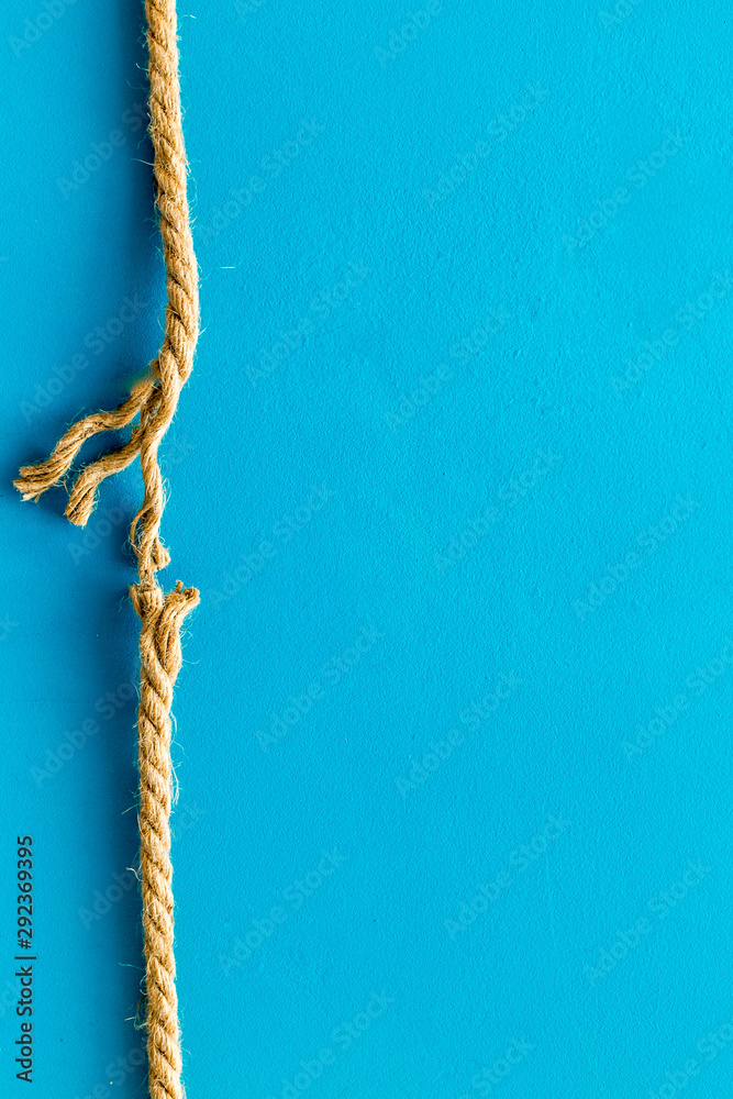 Tearing the rope under stress on blue background top view copyspace