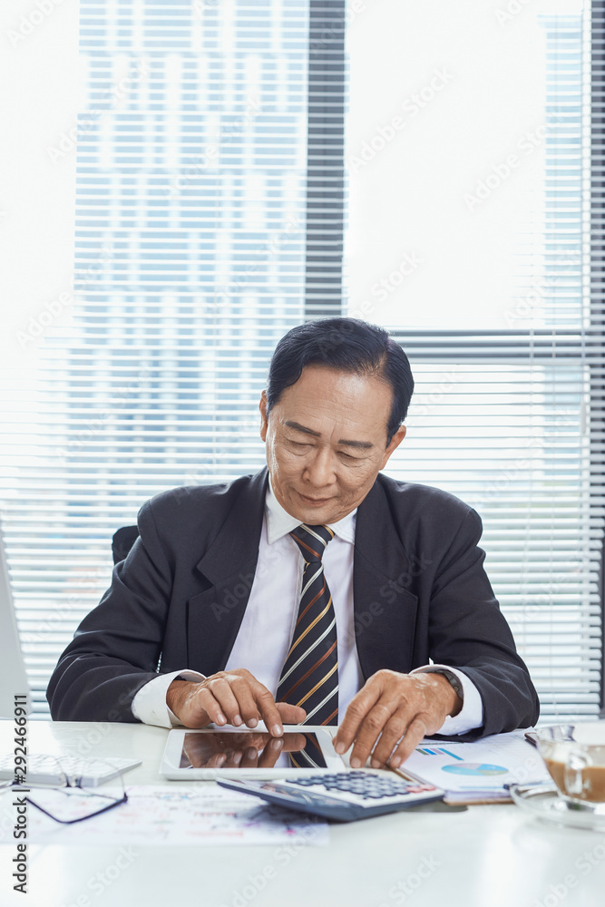 Smiling asian businessman using tablet in office