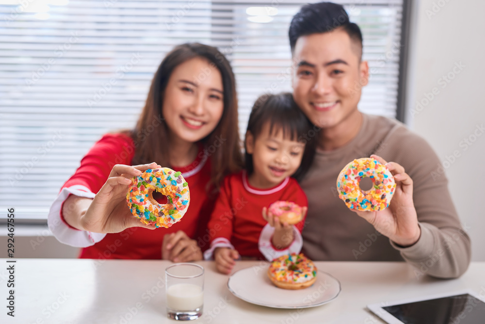 Happy young family with children enjoying breakfast in a white sunny dining room with a big garden v