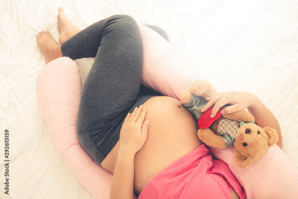 Happy pregnant woman sleeping on bed in bedroom at home for resting and stress relief. The young exp