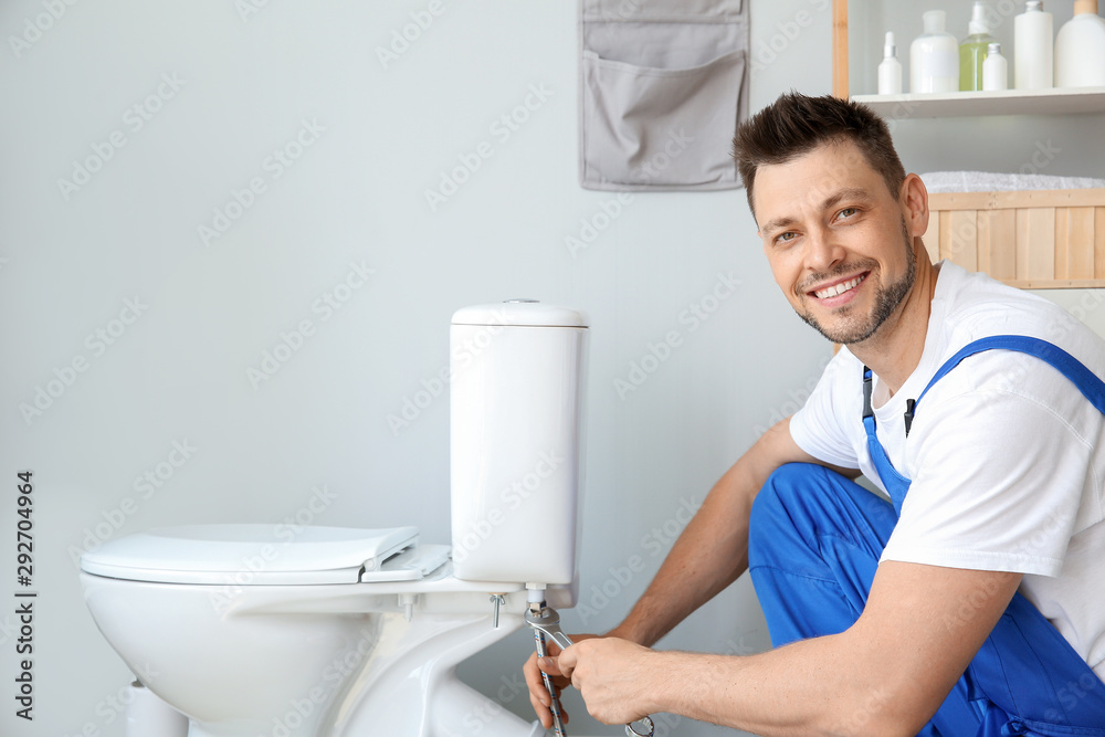 Plumber installing toilet in restroom