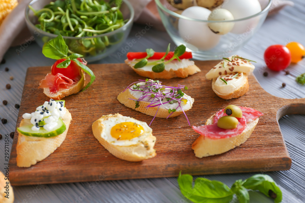 Different tasty sandwiches on wooden board